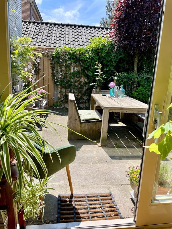De aangrenzende tuin met een zitje, gezien vanuit de praktijkruimte